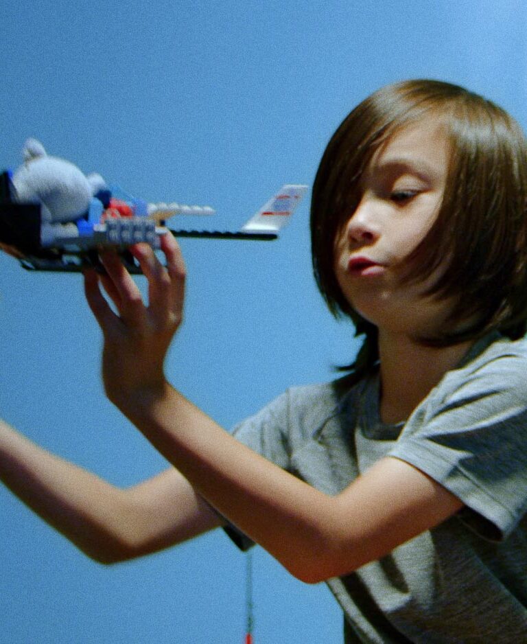 Kai, a young boy, flies a LEGO rocket ship through the air