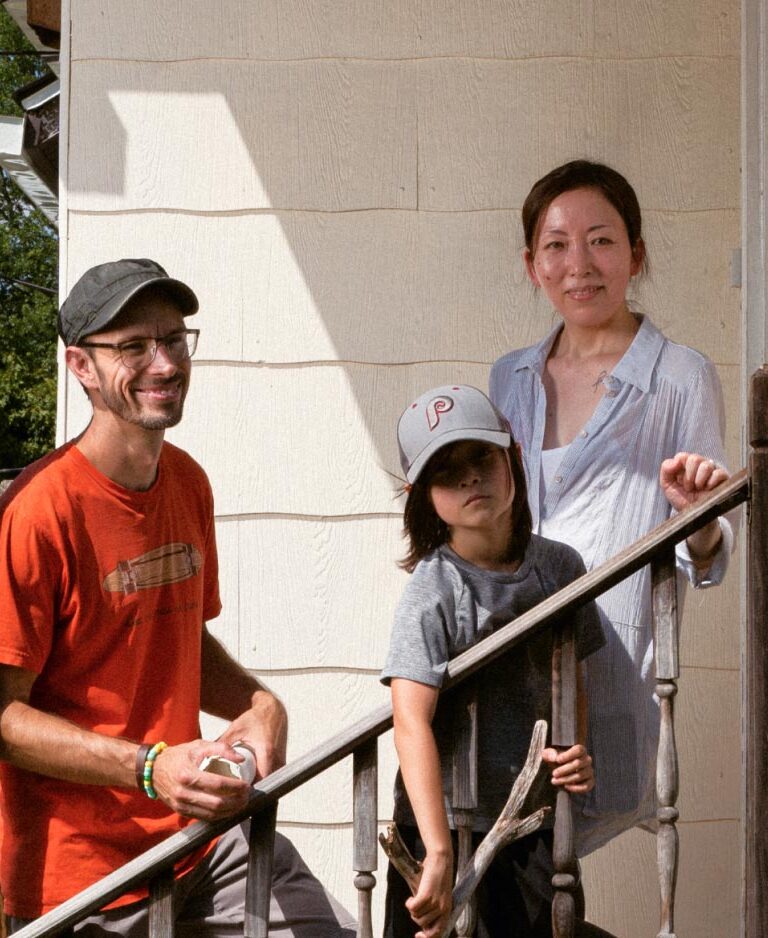 A mother and father smile on a staircase with their young son between them