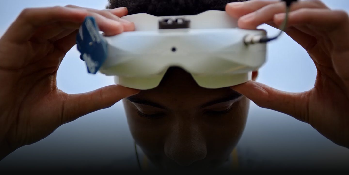 A Black teen boy pulls on drone goggles