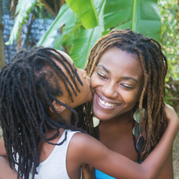 A daughter kissing her mother on the cheek as they embrace in a hug.