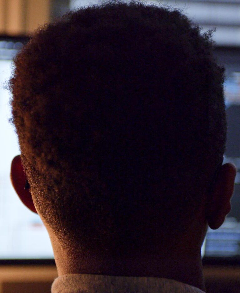 A boy looking at a large computer screen