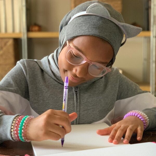 Tween girl draws with a crayon and smiles