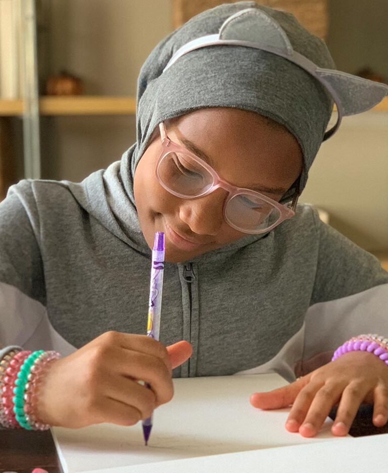 Tween girl draws with a crayon and smiles